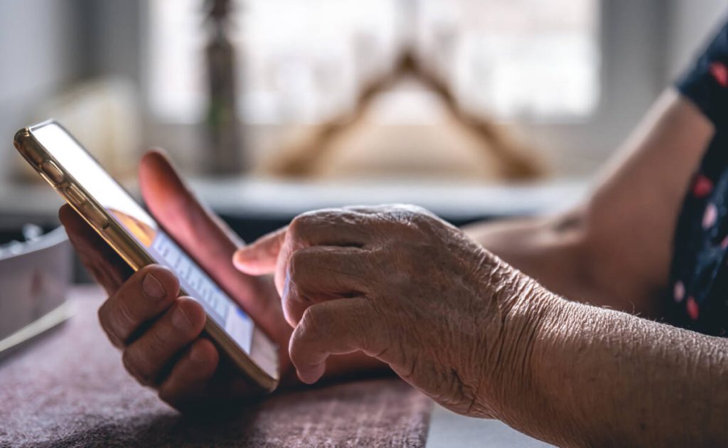 Hands of an elderly woman holding a mobile phone.