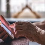 Hands of an elderly woman holding a mobile phone.